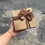 Hộp quà giấy vuông đỏ nắp rời, quai xách, có hoa kim tuyến, rơm và đèn đom đóm